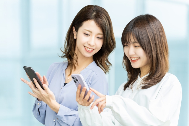 スマホを見て話す2人のビジネスウーマン