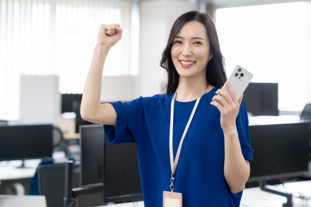 オフィスカジュアルでスマホを持っている若い女性エンジニア